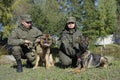 Military handlers and their service dogs German shepherds sitting on a ground after training