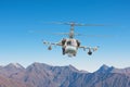 Military helicopter with armament flies on tops of mountains