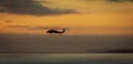 A military helicopter flying toward the left in a cloudy sunset Royalty Free Stock Photo