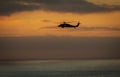 A military helicopter flying toward the left in a cloudy sunset Royalty Free Stock Photo