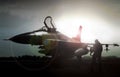 Military jet in silhouette with pilot walking away