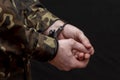 A military man in camouflage is handcuffed on a dark background. Concept: war criminal, prisoner of war, tribunal for deserters, t