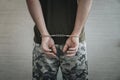 military man in handcuffs on a dark background, selective focus. Concept: war criminal, prisoner of war, tribunal for