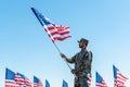 Military man in uniform and cap holding american flag while standing against blue sky Royalty Free Stock Photo