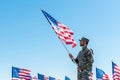 Military man in uniform holding american flag while standing against blue sky Royalty Free Stock Photo