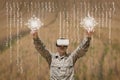 Military man in VR headset touching interfaces against field background with interfaces Royalty Free Stock Photo