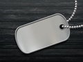 Military metal id tag on a black wooden background