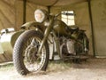 A military motorcycle with a sidecar under an awning. Military camouflage motor vehicles of the Second World War. Royalty Free Stock Photo