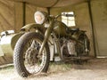 A military motorcycle with a sidecar under an awning. Military camouflage motor vehicles of the Second World War. Royalty Free Stock Photo