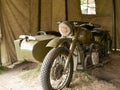 A military motorcycle with a sidecar under an awning. Military camouflage motor vehicles of the Second World War. Royalty Free Stock Photo