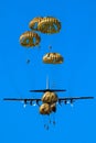 Military parachutist paratroopers parachute jumping out of a air force planes on a clear blue sky day