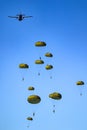 Military parachutist paratroopers parachute jumping out of a air force planes on a clear blue sky day