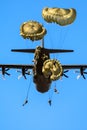 Military parachutist paratroopers parachute jumping out of a air force planes on a clear blue sky day