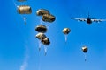 Military parachutist paratroopers parachute jumping out of a air force planes on a clear blue sky day