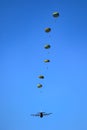 Military parachutist paratroopers parachute jumping out of a air force planes on a clear blue sky day