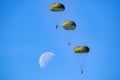 Military parachutist paratroopers parachute jumping out of a air force planes on a clear blue sky day with the moon