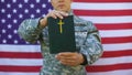 Military peacekeeper showing bible, american flag background, faith symbol hope