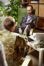 Military person having therapy session. Psychologist consults female soldier. Post-traumatic syndrome, specialist help Royalty Free Stock Photo