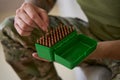 Man of arms removing single ammunition round from box Royalty Free Stock Photo