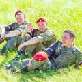 Military police soldiers resting sitting on the grass on a summer sunny day. Text in Russian: police, Armed forces of Russia, Sul