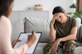 Military psychiatry concept. Depressed soldier lady sitting on couch during therapy session