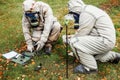 Military scientists in protective suits check radiation levels in open areas outside. Measurement of environmental