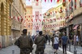 Military security armed police walk through Old Vieux Nice, France, towards Rusca Palace as flags drape across the alley