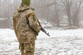 A military soldier in camouflage with a Kalashnikov assault rifle is waiting for an order