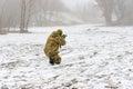 A military soldier in camouflage with a weapon goes on the offensive in winter