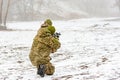 A military soldier in camouflage with a weapon goes on the offensive in winter