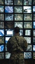 A military strategist studies a wall of monitors each screen a window into the complexities of global security Royalty Free Stock Photo
