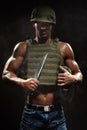 Military style muscle man in tactical vest and helmet posing with survival knife