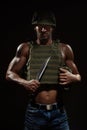 Military style muscle man in tactical vest and helmet posing with survival knife