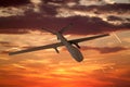 military UAV airplane flies against backdrop of beautiful sunset sky is orange with clouds and condensation traces Royalty Free Stock Photo