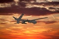 military UAV airplane flies against backdrop of beautiful sunset sky is orange with clouds and condensation traces Royalty Free Stock Photo