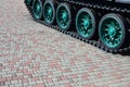 A military vehicle on caterpillar tracks stands on a square of paving stones. Photo of green caterpillars with metal wheels that Royalty Free Stock Photo