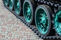 A military vehicle on caterpillar tracks stands on a square of paving stones. Photo of green caterpillars with metal wheels that Royalty Free Stock Photo