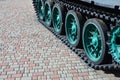 A military vehicle on caterpillar tracks stands on a square of paving stones. Photo of green caterpillars with metal wheels that Royalty Free Stock Photo