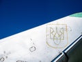 Military war jet airplane tail with Ukrainian air defense logo against blue sky. Old, worn out and rough shiny metal surface. Royalty Free Stock Photo