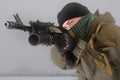 Militiaman in russian pattern uniform with kalashnikov ak-47 rifle with under-barrel grenade launcher at snow field near abandoned