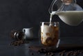 Milk Being Poured Into Glass Iced Coffee on a gray background Royalty Free Stock Photo