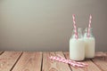 Milk bottles with retro striped straws on wooden table Royalty Free Stock Photo