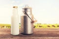 Milk can and bottle on table near the cow pasture meadow Royalty Free Stock Photo