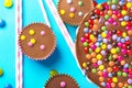 Milk chocolate birthday cake with multicolored glazed candy sprinkles decoration peanut butter cups on blue background. Kids party Royalty Free Stock Photo