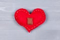 Milk chocolate square on red homemade heart on grey wood.