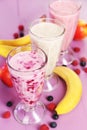 Milk cocktail with banana, blackcurrant and raspberry in a glass on purple wooden background Royalty Free Stock Photo