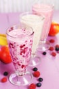 Milk cocktail with banana, blackcurrant and raspberry in a glass on purple wooden background. Royalty Free Stock Photo
