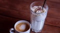 Milk cocktail in high glass and mug of hot latte coffee standing on wooden table. Two drinks, cold and hot, on brown table Royalty Free Stock Photo