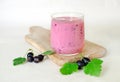 Milk coctail with black currant berries in glass cup on wooden board with bunches of black currant. light background. side view Royalty Free Stock Photo