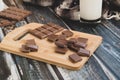 Milk dark chocolate tiles on wood cutting board, wooden background Royalty Free Stock Photo